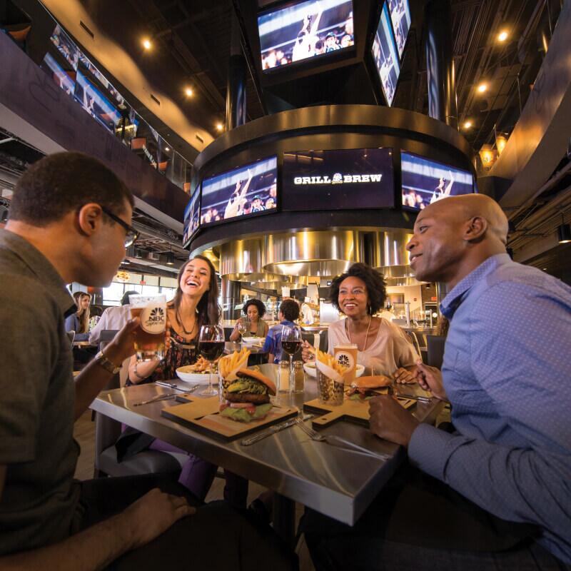 Friends eating and talking at NBC Sports Grill and Brew.