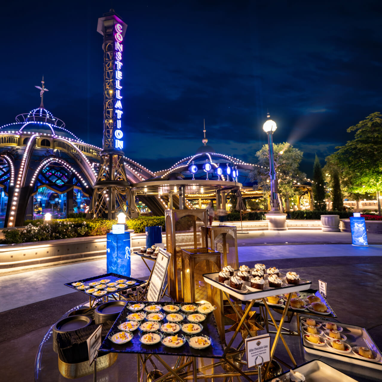 Event setup with desserts displayed outside Atlantic restaurant in Celestial Park at night at Universal Epic Universe.