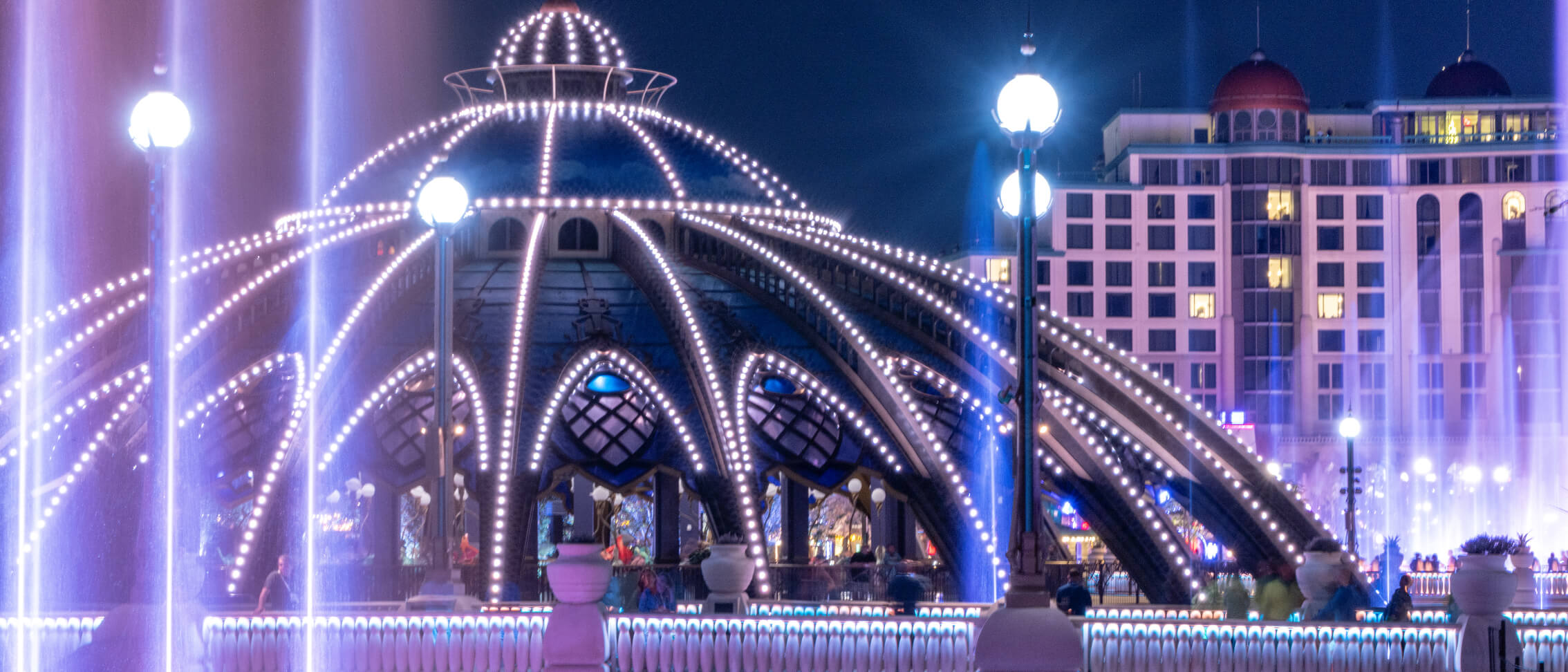 Illuminated fountains and architecture at night in Celestial Park at Universal Epic Universe.