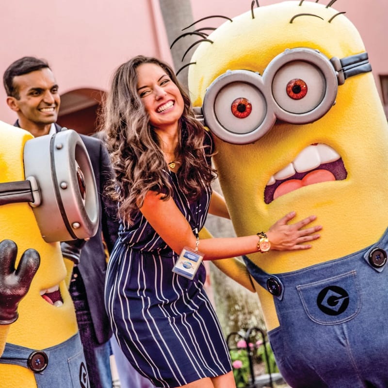A woman smiling on a red carpet with one of Gru's Minions