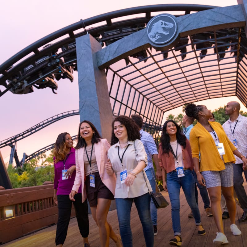 Guests walking with Jurassic World VelociCoaster in the background.