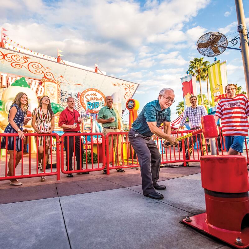 Attendees playing the strongman hammer game at Krustyland at Universal Studios Florida