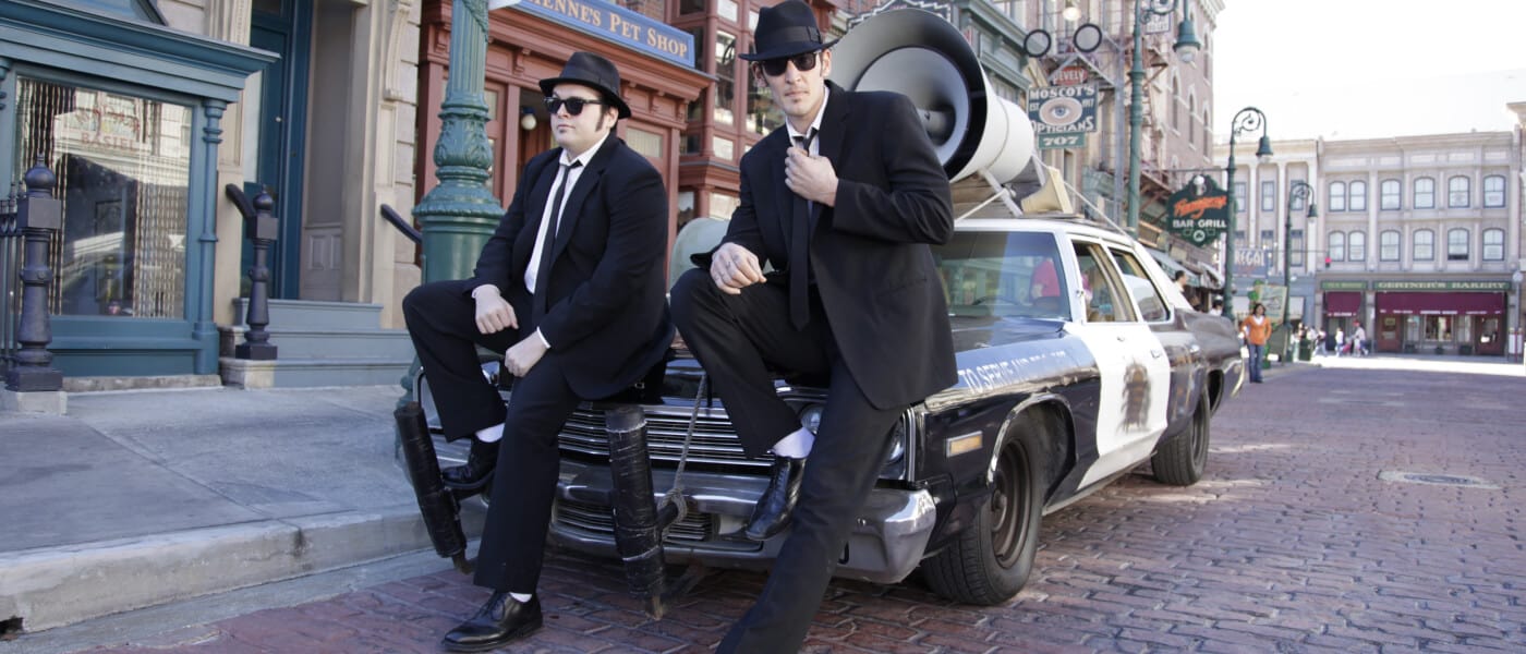 Blues Brothers pose in front of a police car