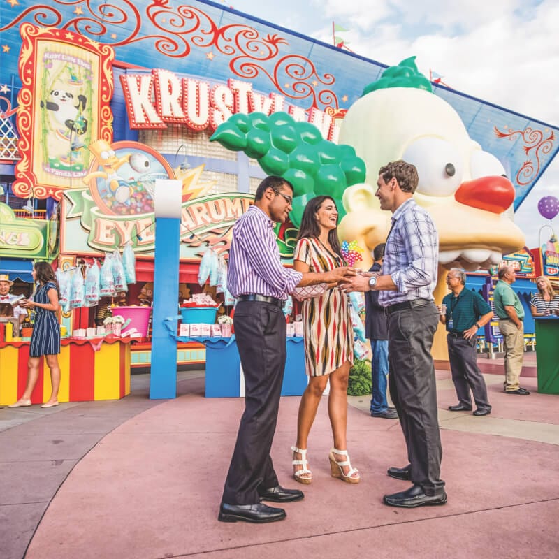 A group of adults chatting outside a Simpsons attraction