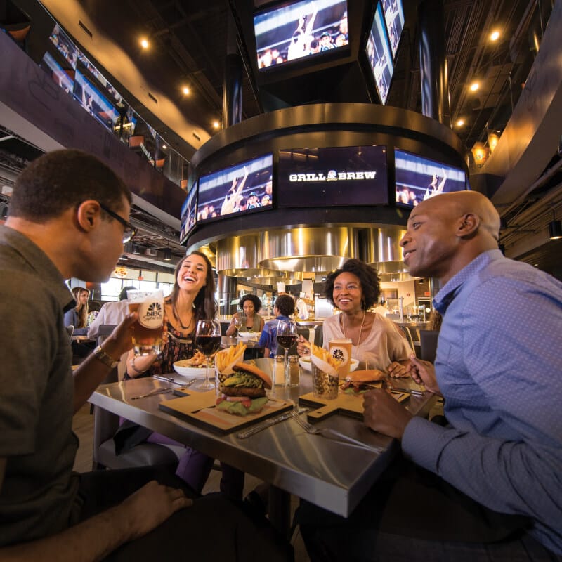 Friends eating and talking at NBC Sports Grill and Brew.