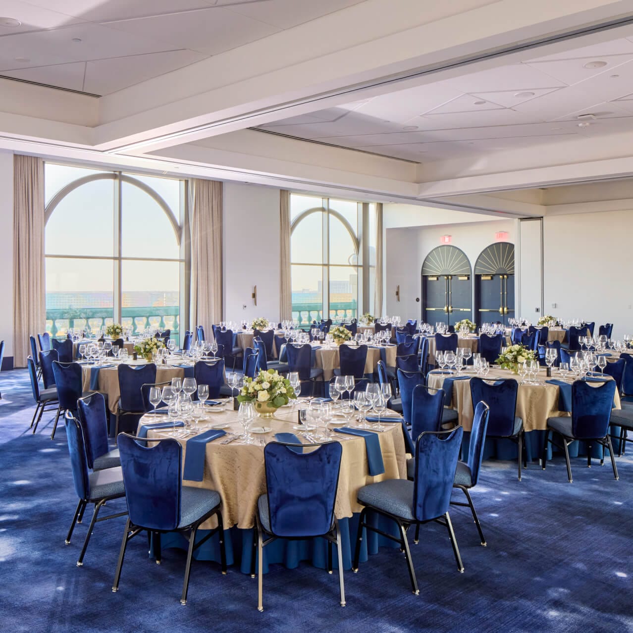 The grand hall of the Universal Helios Grand Hotel, a Loews Hotel, complete with table settings and floral centerpieces.