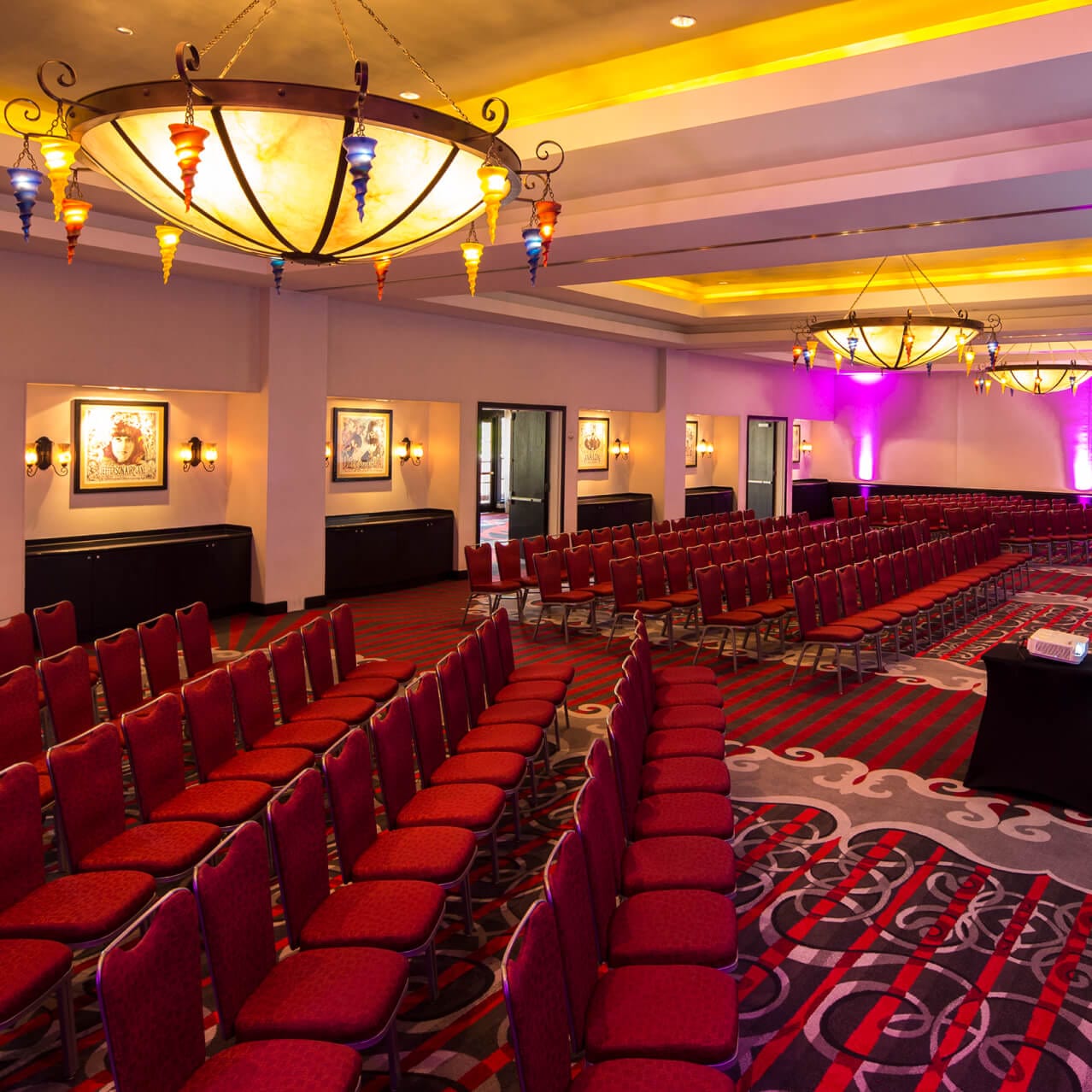 Avalon Ballroom with rows of red chairs under large decorative chandeliers and warm ambient lighting.