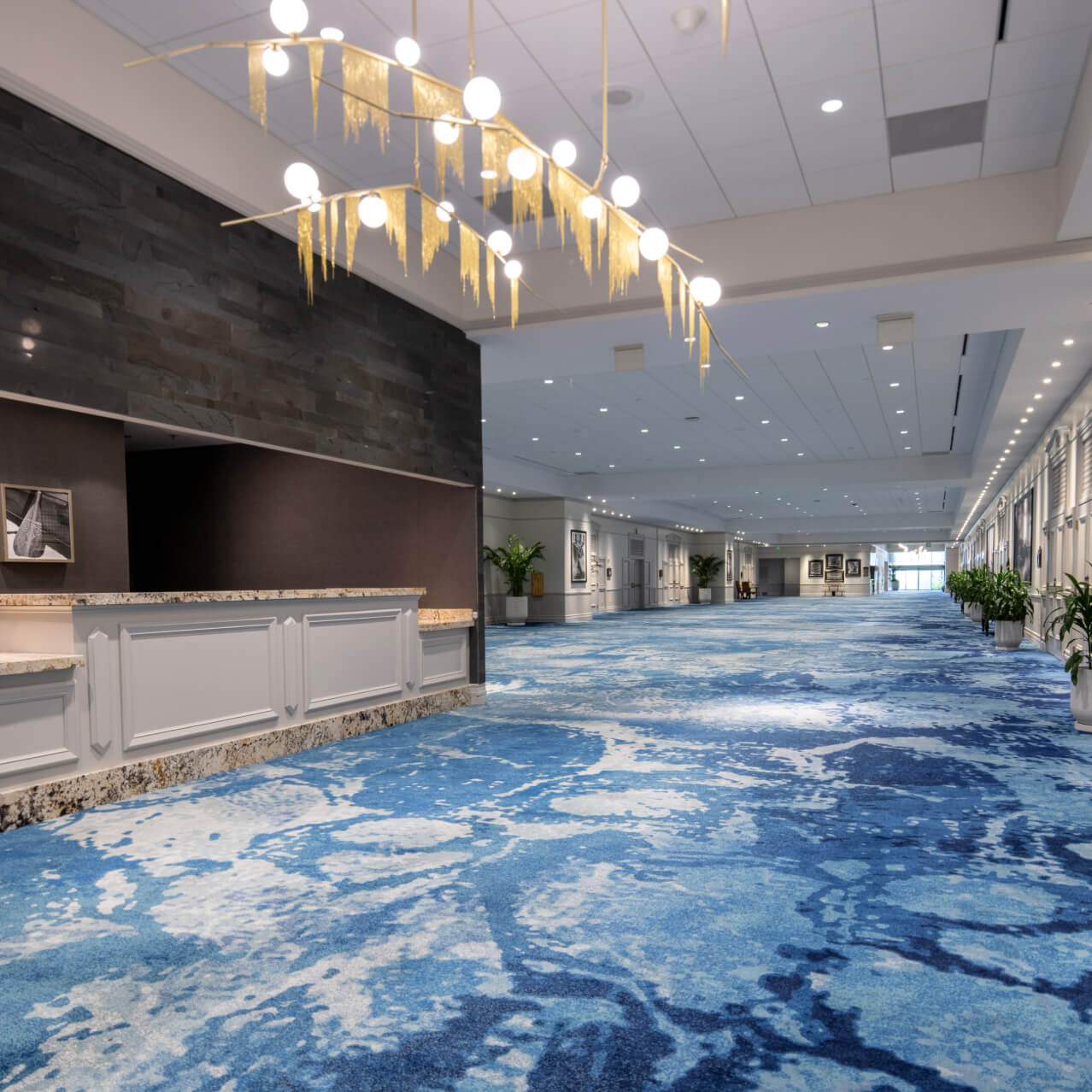 Spacious pre-function hallway at Loews Royal Pacific Resort featuring a white registration desk and blue patterned carpet.