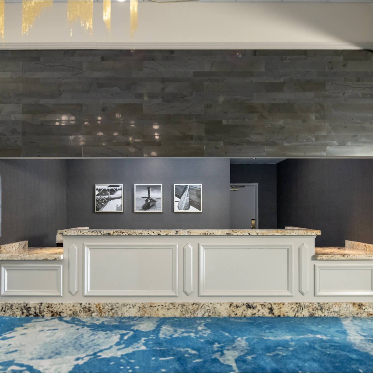 Registration desk for meetings and events at Loews Royal Pacific Hotel, featuring a white paneled front, granite tops, and a dark stone feature wall.