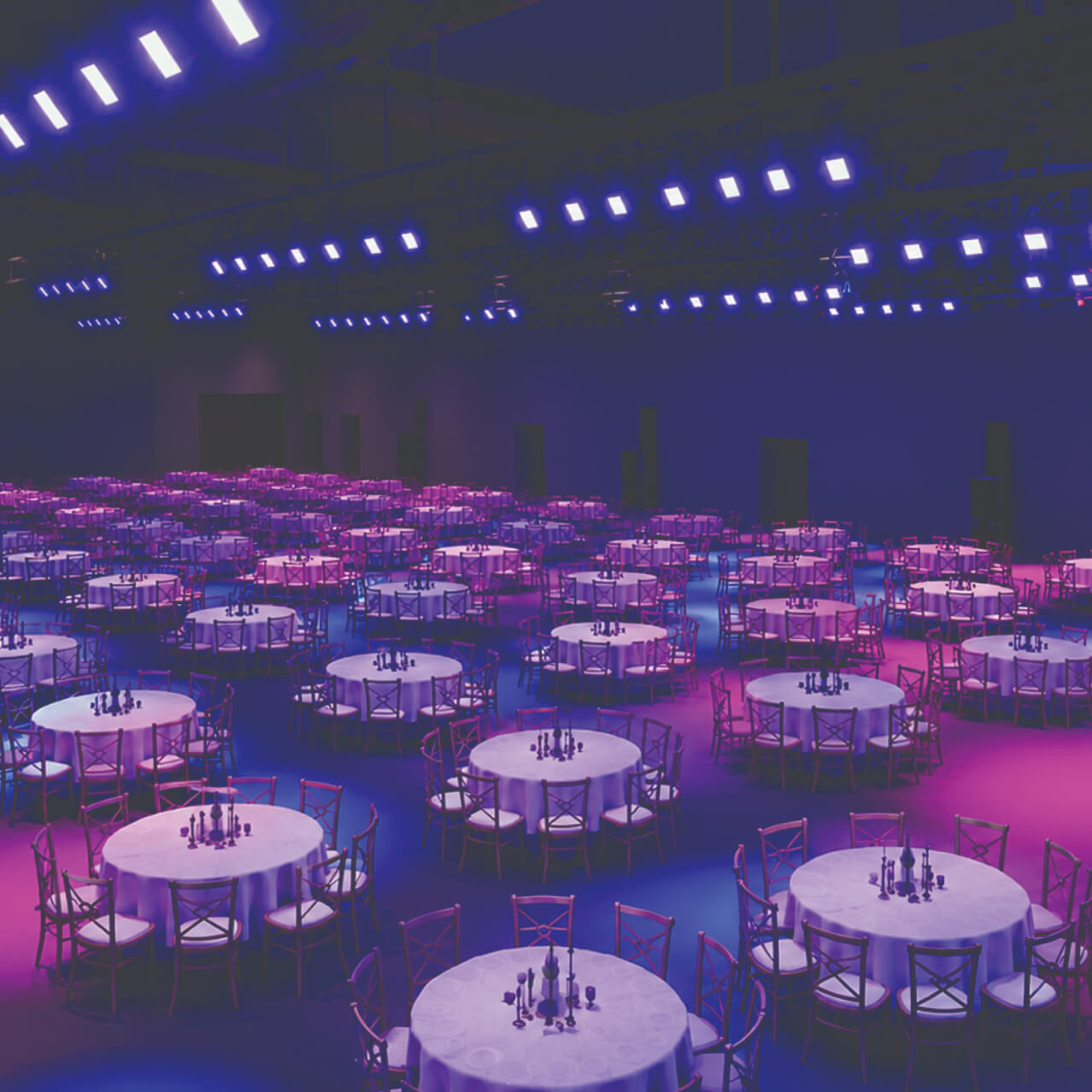 A large, dimly lit banquet hall at Celestial Expo filled with round tables, chairs, and dark centerpieces under purple and blue ambient lights.