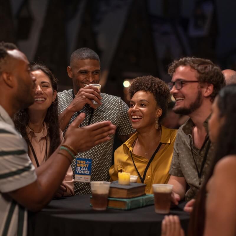 Event attendees talking and enjoying Butterbeer while standing at a table in Hogsmeade.