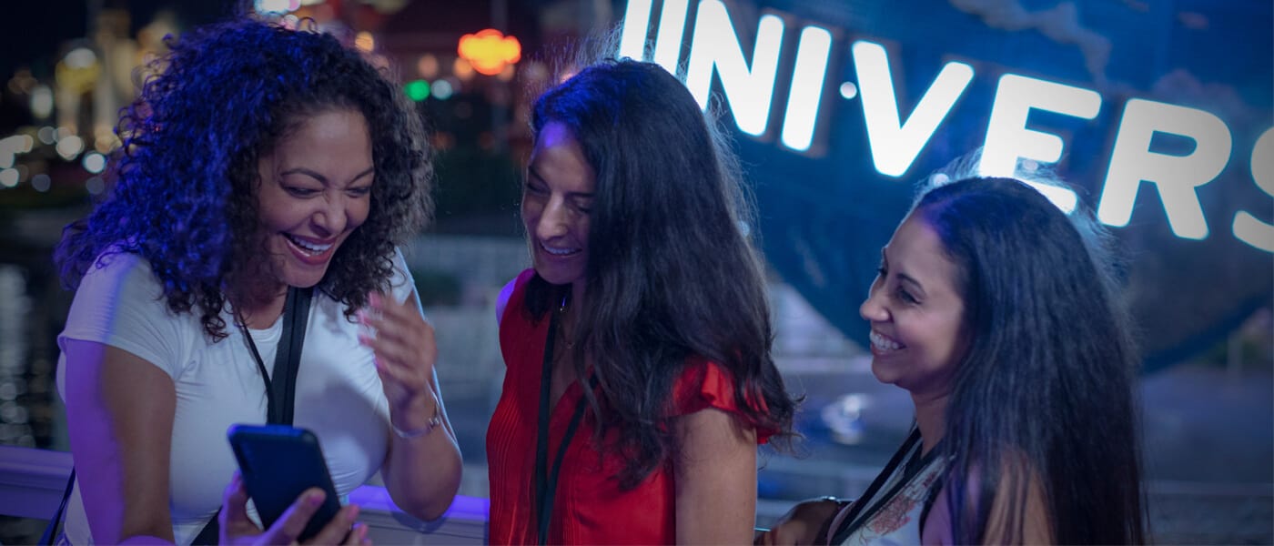 Three friends laughing in front of the Universal globe