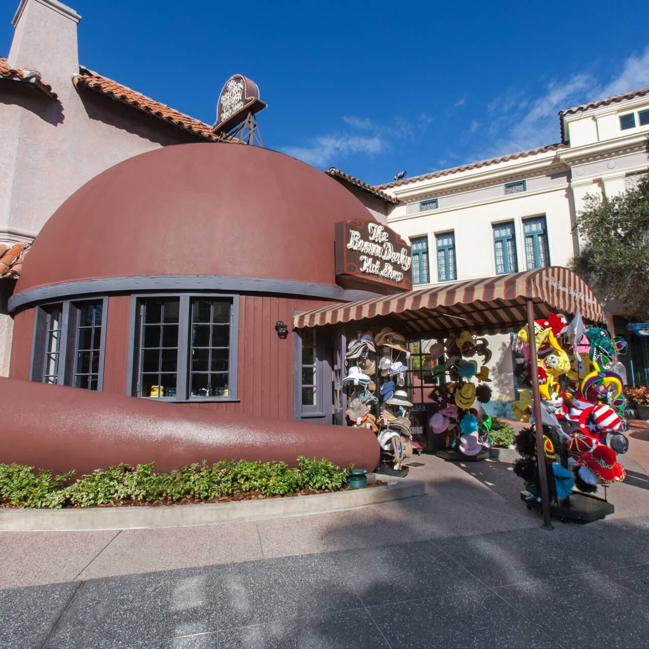 The Brown Derby Hat Shop located in the Hollywood area of Universal Studios Florida is shaped like a large hat with windows and an awning.