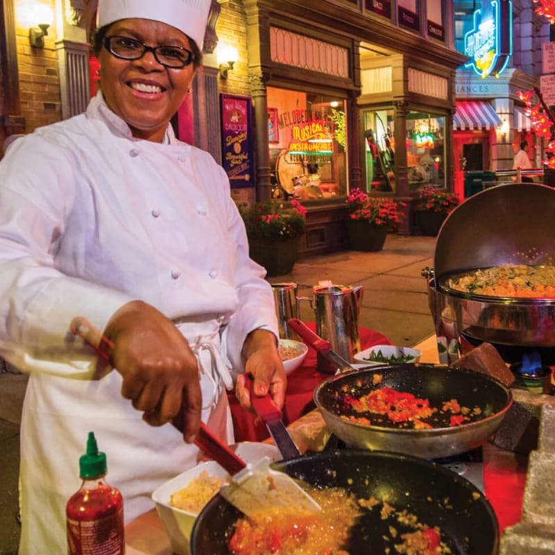 A chef smiles while cooking outdoors