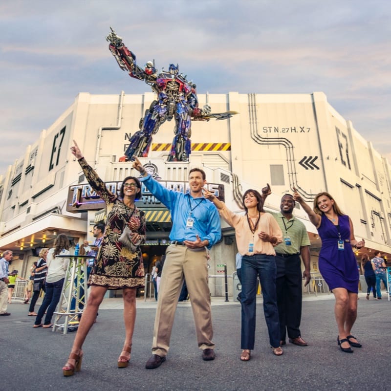 A group of adults pointing with Optimus Prime of the Transformers.