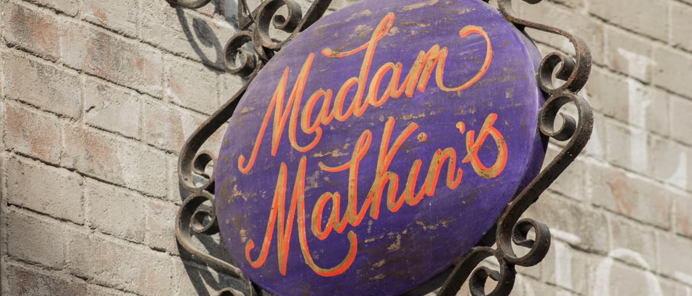 picture of a purple sign with red writing for the Malkins Robes shop; it reads Madam Malkin's