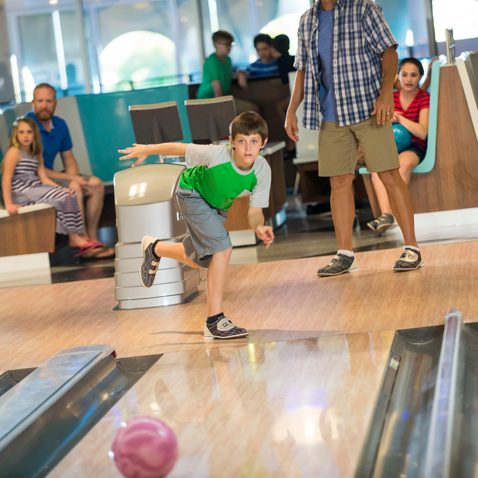 A boy throws a bowling ball down the lane at Galaxy Bowl, a fun, retro bowling alley at Universal Orlando's Cabana Bay Beach Resort.