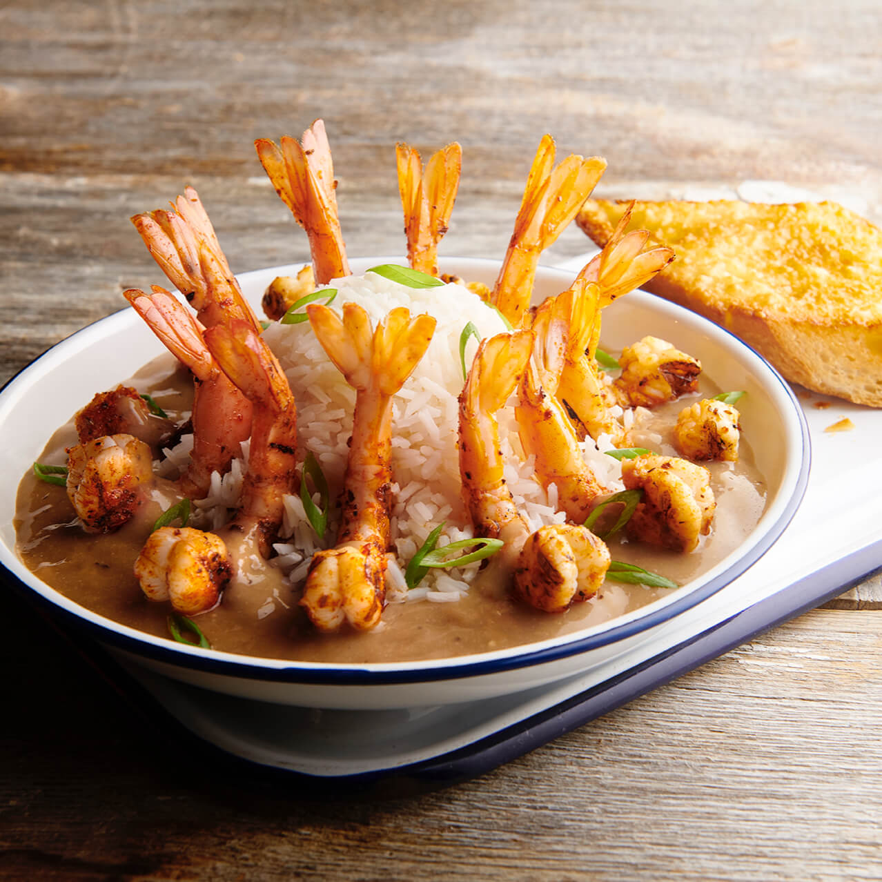 Bubba Gump Shrimp Co.'s SHRIMP NEW ORLEANS plate at CityWalk Orlando, featuring Grilled Shrimp, Spicy New Orleans Sauce, Green Onions and Tomatoes over Steamed Rice with a side of Garlic Bread.