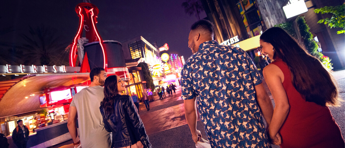 Friends walking and laughing together through Universal CityWalk at nighttime.