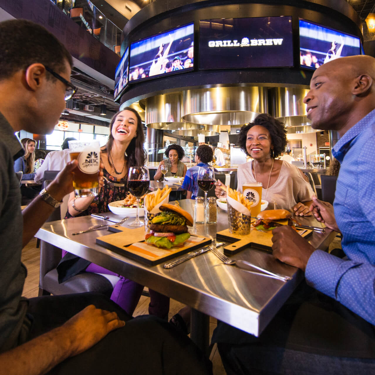 A group of friends dine at a square table inside NBC Sports Grill And Brew, an innovative restaurant at Universal Orlando's CityWalk.