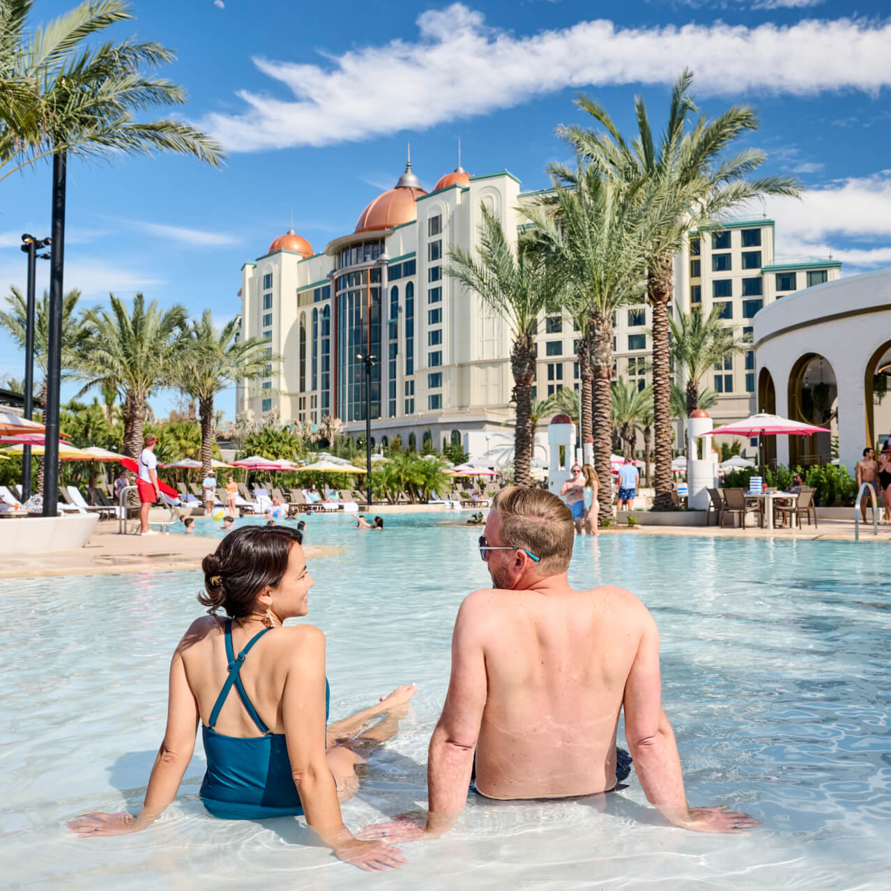 A couple enjoying a soak in the zero-entry pool at Universal Helios Grand Hotel, a Loews Hotel.
