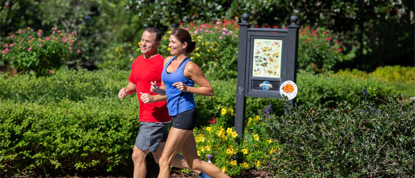 A couple runs on a sidewalk on the walking and jogging path that connects Universal Orlando's on site resorts and theme parks.