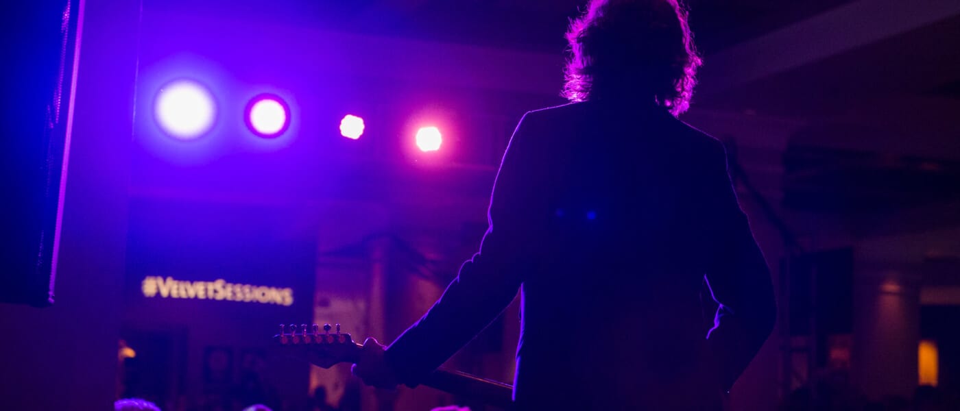 The silhouette of a man holding a guitar looking out into the audience at Velvet Sessions, a close up concert series at Hard Rock Hotel in Universal Orlando.