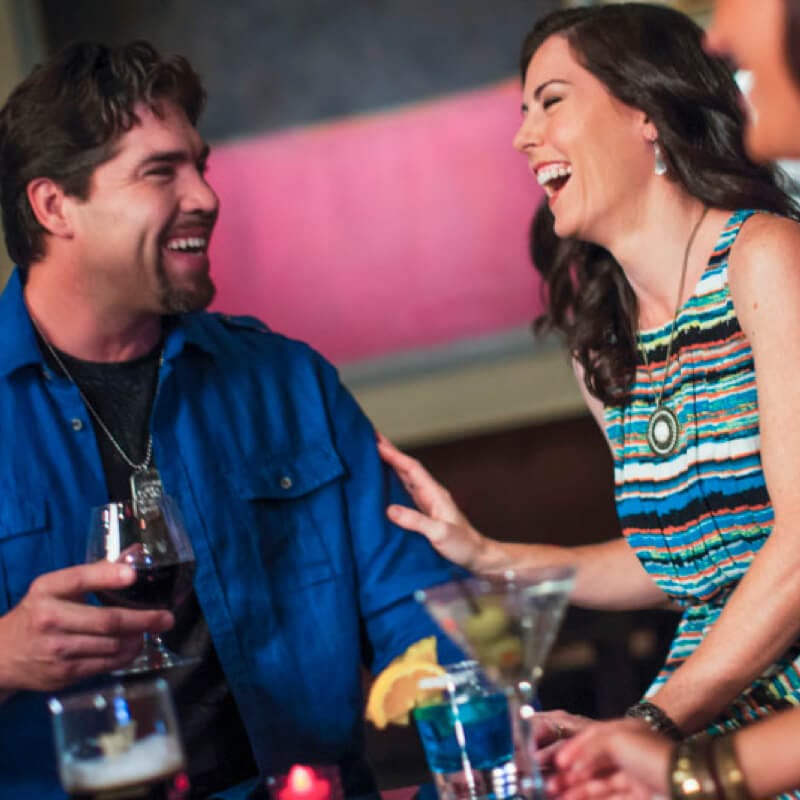 A group of adults sit around a table laughing and smiling while enjoying drinks at Velvet Bar in Hard Rock Hotel, a Premier on site resort hotel at Universal Orlando Resort.