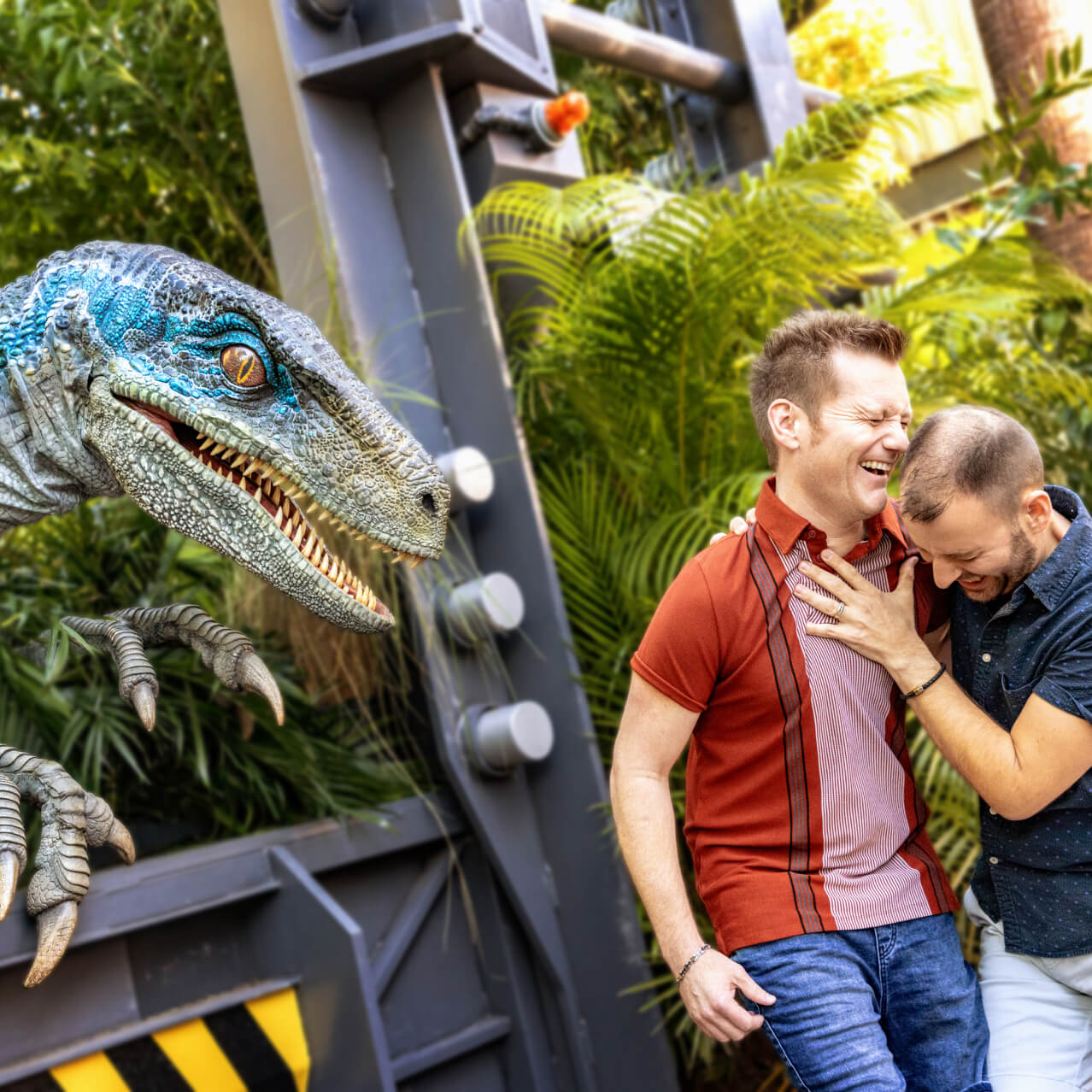 A couple hugging and laughing with relief after being scared by Blue the velociraptor, still lurking nearby.