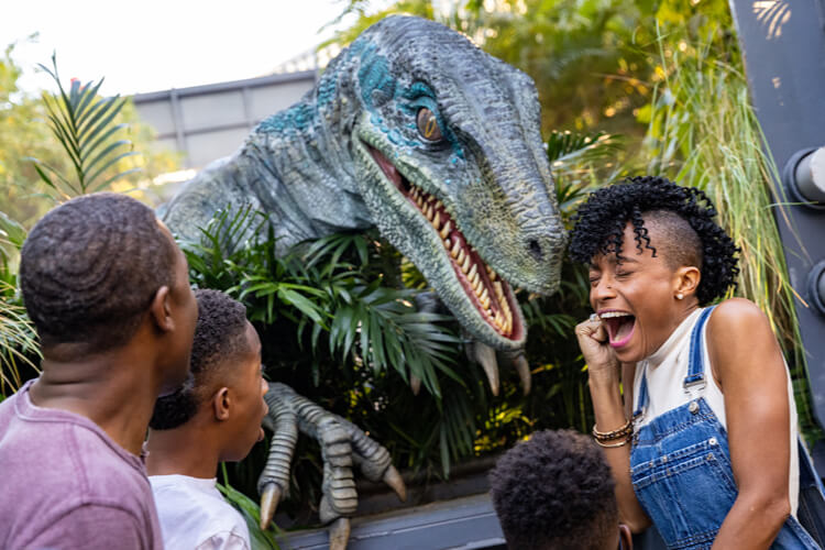 A family reacts as Blue the Velociraptor jumps out and bares her teeth in a Paddock at Universal Islands of Adventure.