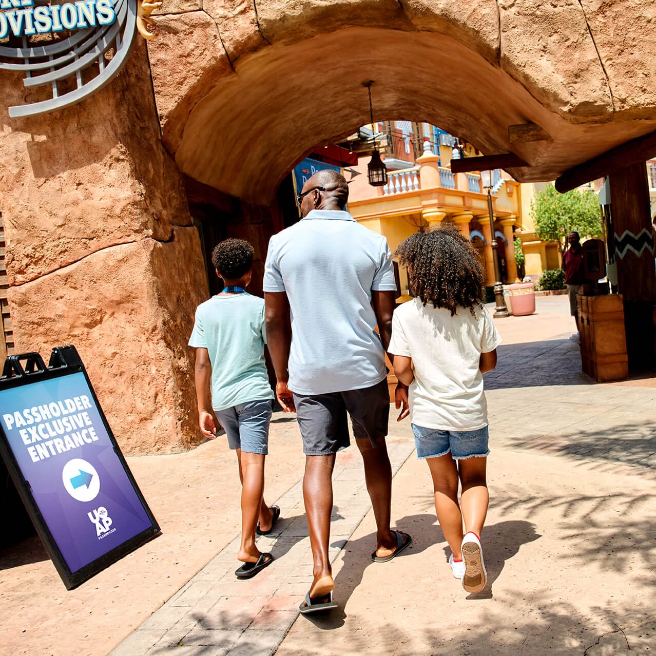 A family of three walking towards the Passholder Exclusive Entrance to Islands of Adventure.