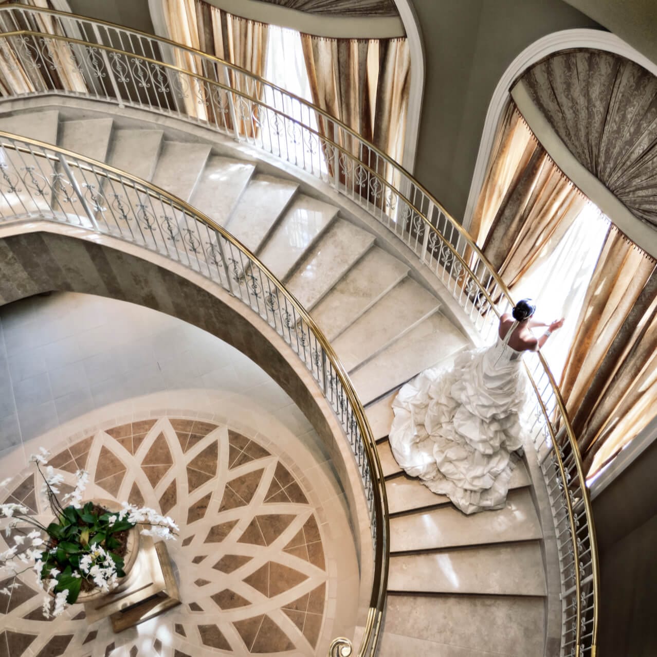 A bride peaks through the curtains of a grand window from a spiral staircase at Loews Portofino Bay Hotel at Universal Orlando.
