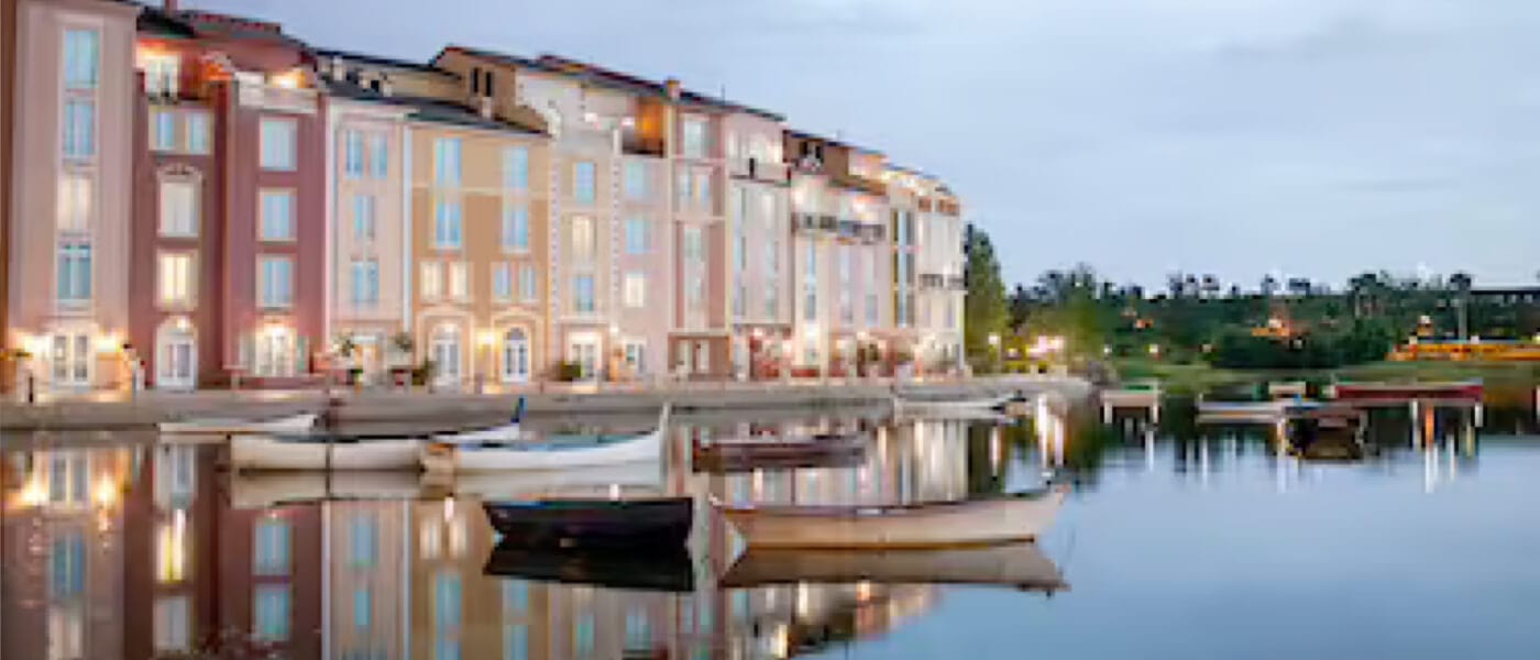 Boats float in the water as street lights illuminate the walkways of the Harbour Piazza of Loews Portofino Bay Hotel, one of the Premier on-site resort hotels at Universal Orlando.
