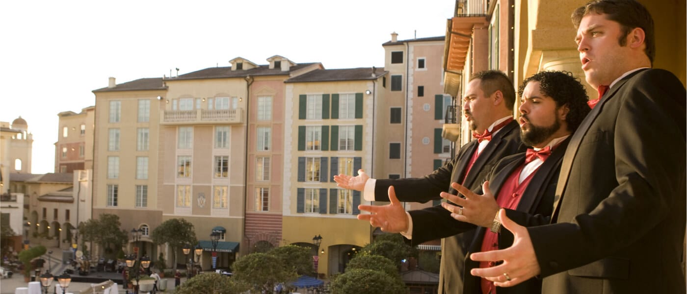 Three men in suits belt out operatic melodies from a balcony overlooking the Piazza at Loews Portofino Bay Hotel in Universal Orlando.