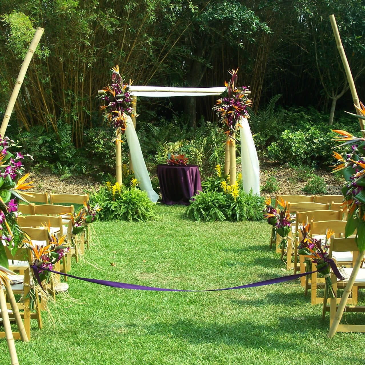 A tropical, South Seas inspired wedding ceremony set up at Loews Royal Pacific Resort in Orlando, complete with bird of paradise flowers and an island arch at the end of the aisle.