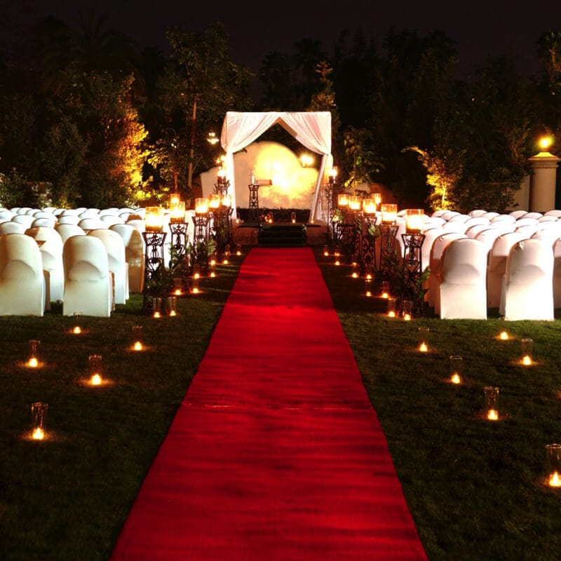 An evening wedding ceremony set up at Universal Orlando's Hard Rock Hotel, complete with a red carpet for the bride to walk down and romantic candles lining the aisle.