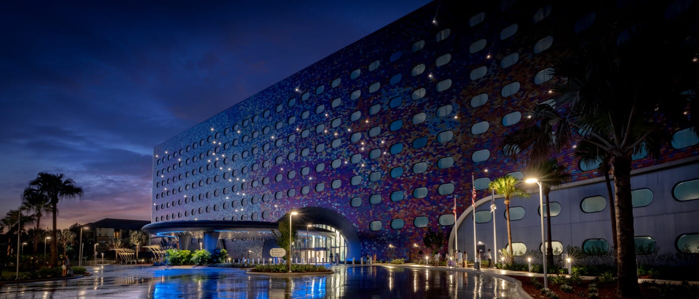 Universal Stella Nova Resort's exterior facade glowing in the moonlight with a sunset in the background.