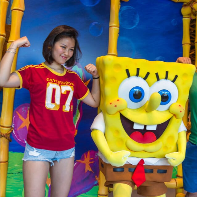 A woman flexes her muscles as she poses alongside SpongeBob SquarePants, who is also flexing his muscles, inside SpongeBob StorePants, a souvenir shop at Universal Studios Orlando.