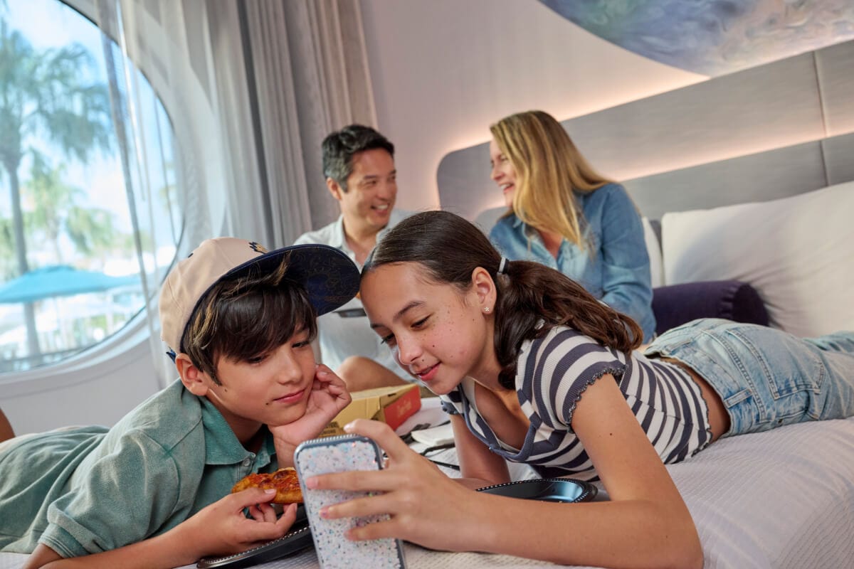 A young family of four enjoying pizza in their hotel room at Universal Terra Luna Resort.