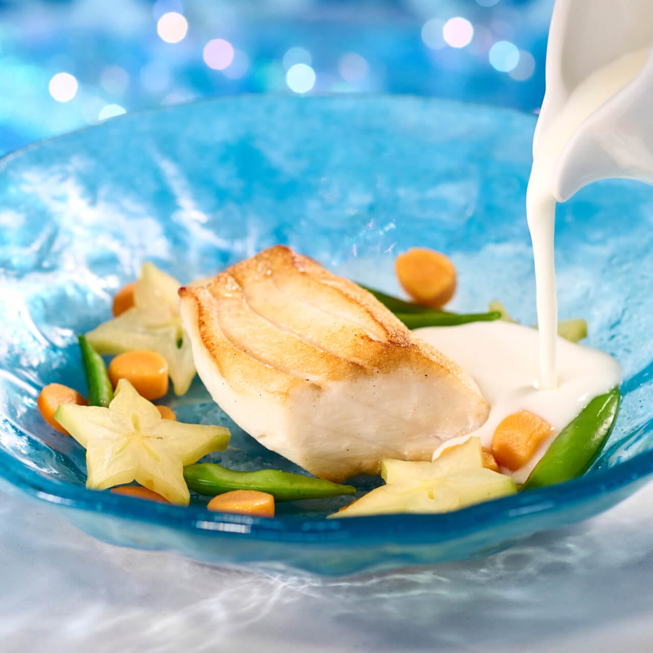 Sea Bass with sugar snap peas, star fruit and broth, in a blue glass dish, served at Atlantic in Celestial Park.