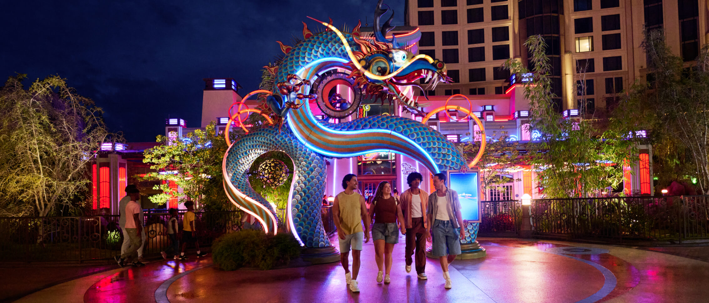 A group of Guests exiting The Blue Dragon Pan-Asian Restaurant under a large, colourful dragon archway at night.
