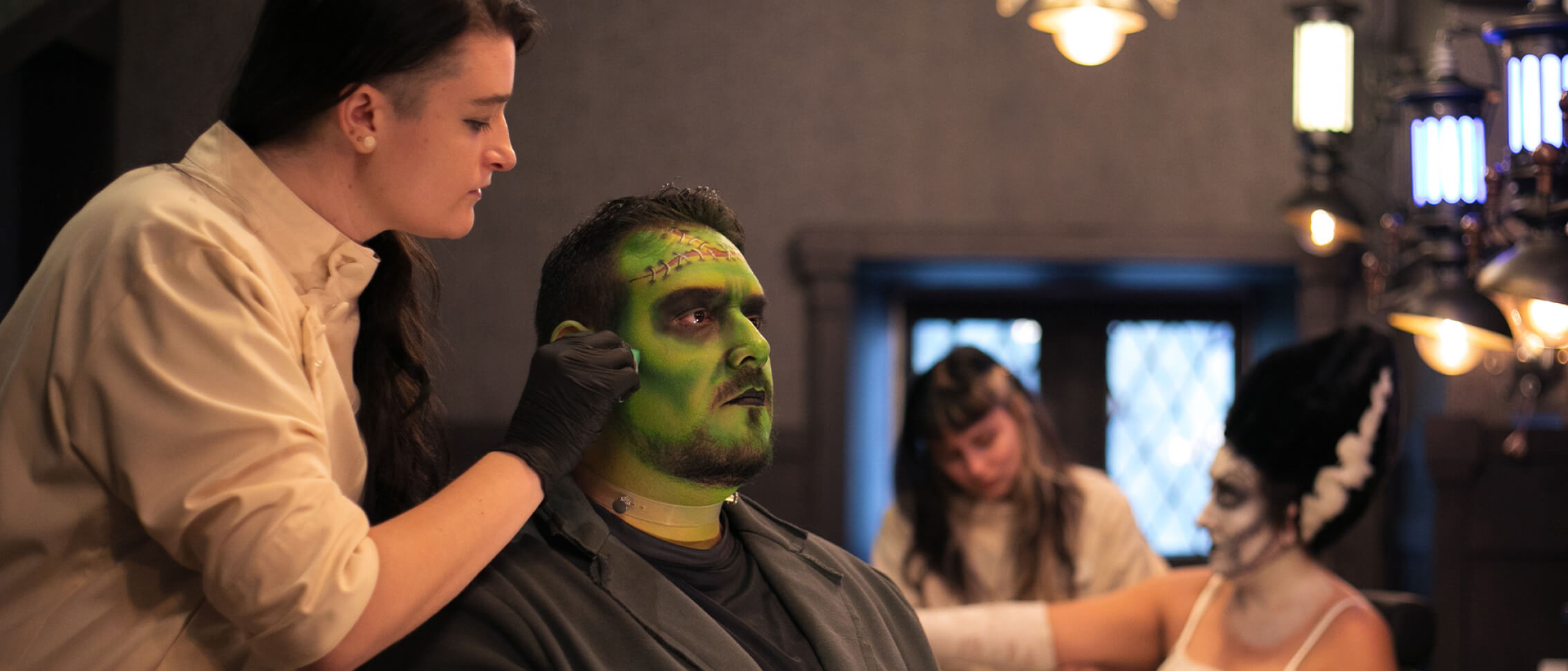 A skilled artist of Darkmoor Monster Makeup Experience works on a customer's face makeup, transforming him into Frankenstein's monster.