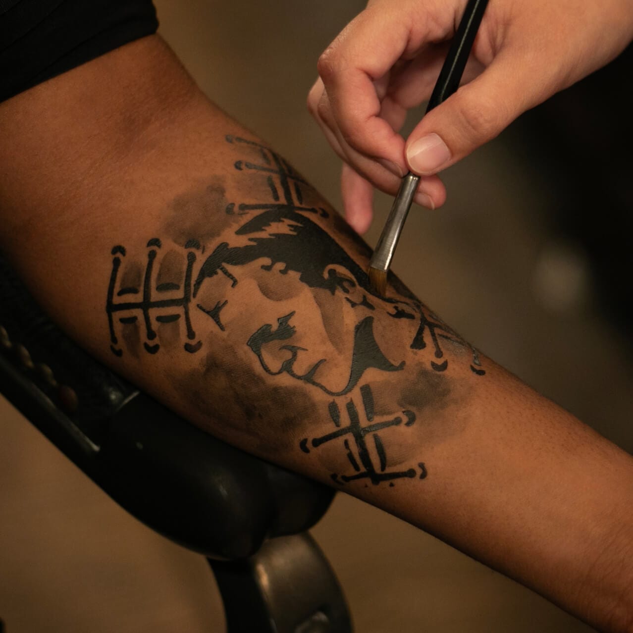 An artist at the Darkmoor Monster Makeup Experience applying a Frankenstein temporary tattoo to a customer's arm.