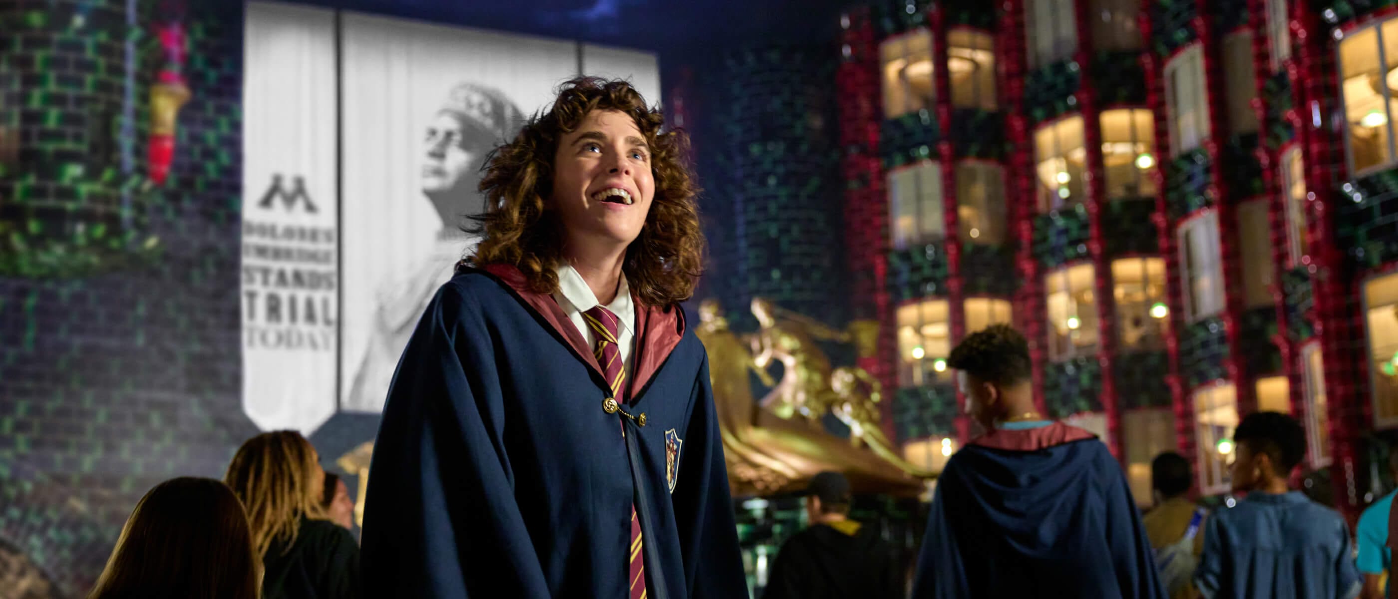 An awestruck fan in wizarding robes with the golden statues, offices and banners of the Ministry of Magic™ in the background.