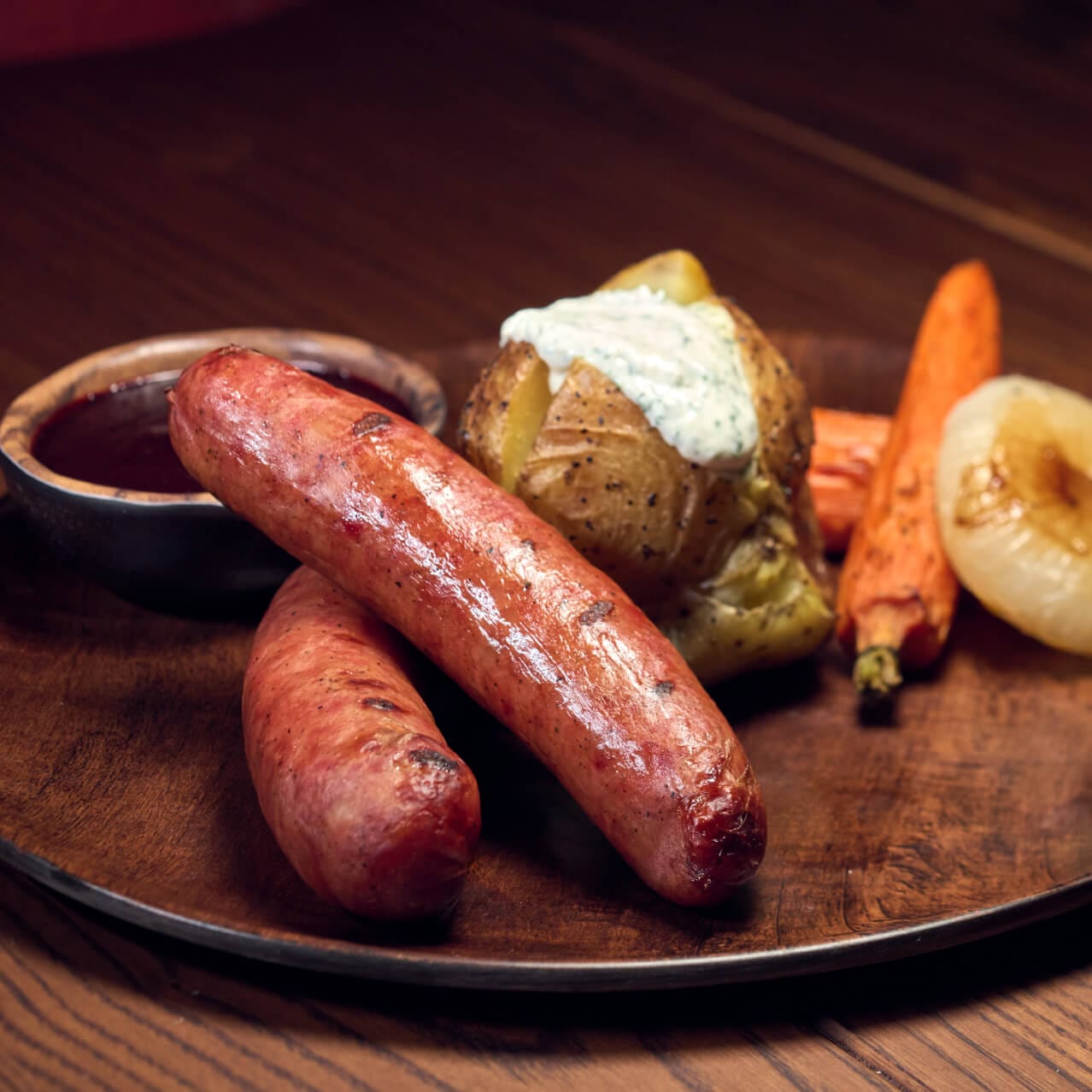 Hooligan's Sausage Links entree, featuring Smoked sausage links, herb garlic potatoes, roasted carrots, Cipollini onions, wild berry BBQ sauce, served at Mead Hall.
