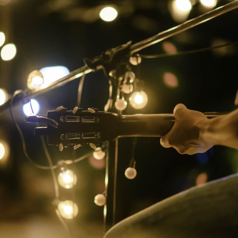 A person playing live music with a guitar and mic stand.
