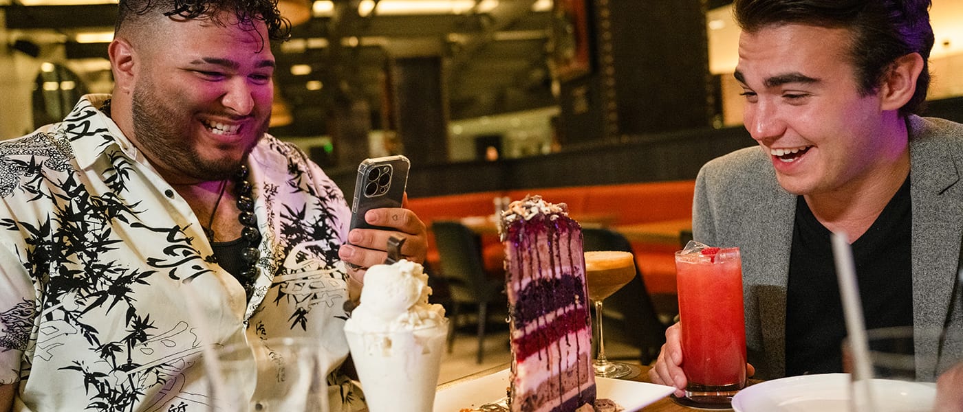 Two men taking a photo of a large dessert at The Kitchen Restaurant at Hard Rock Hotel in Universal Studios Orlando.