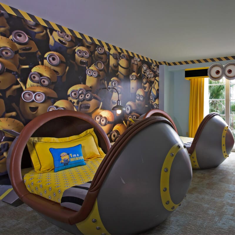 Minion-themed children’s hotel room with two bomb-shaped beds and a wall filled with images of countless Minion characters.