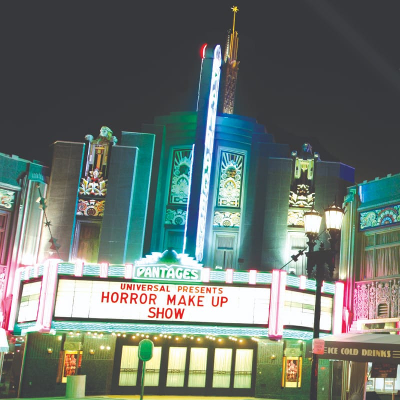 Entrance to the Horror Make-Up Show and the rest of Hollywood at Universal Studios Florida lit up at night.