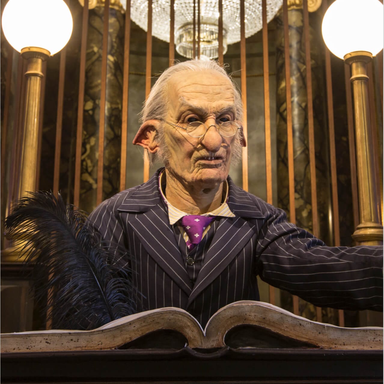 A Gringotts bank goblin looking up at passers-by as they prepare to ride the thrilling Harry Potter and the Escape from Gringotts at Universal Studios Orlando.